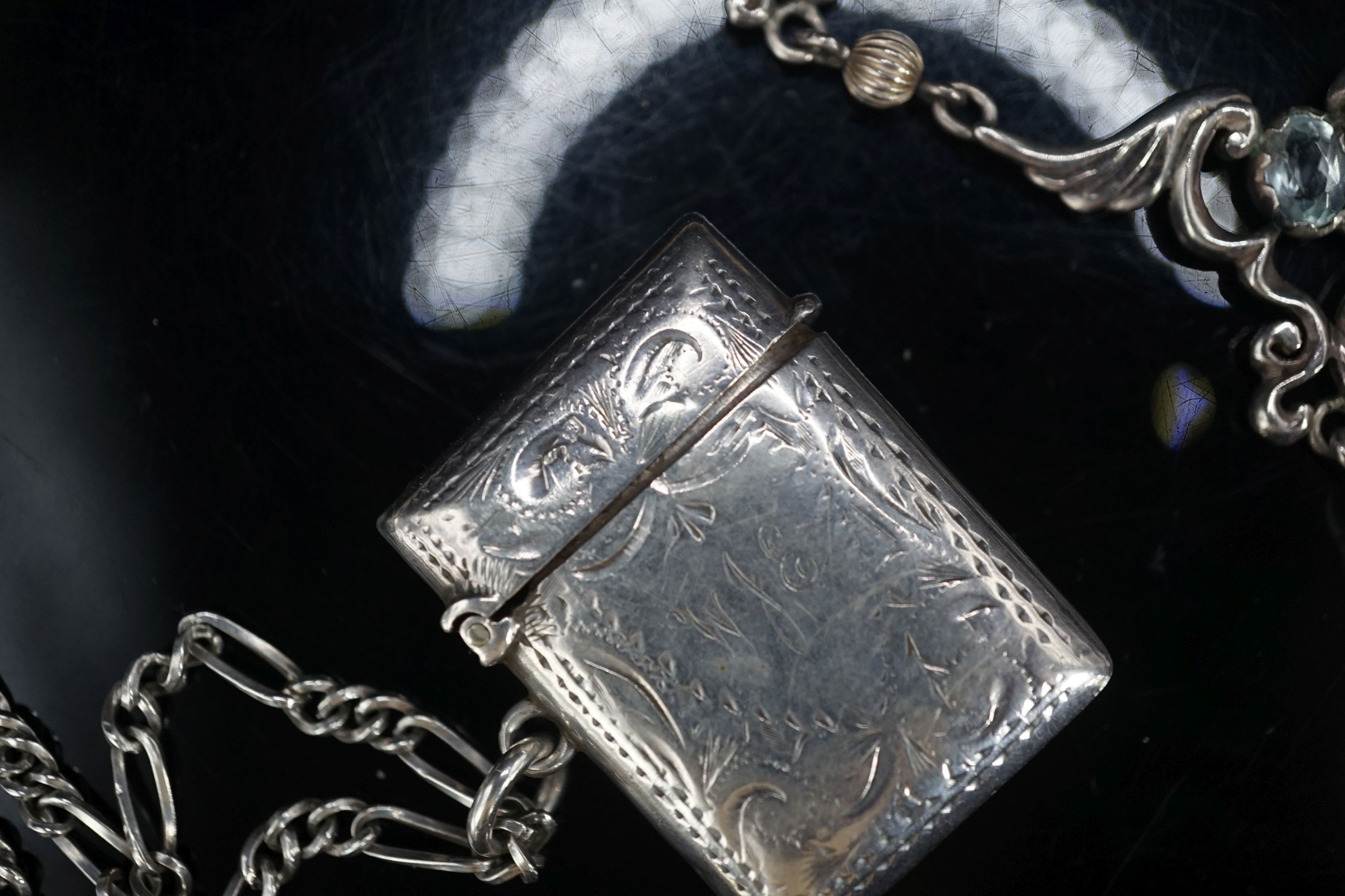 A modern silver pendant necklace, a silver vest case and a sterling chain.